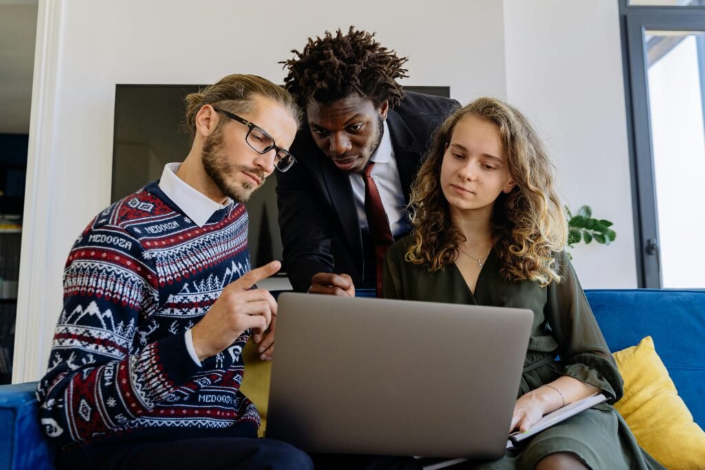 A diverse team of professionals collaborating on a laptop in a modern office setting.
